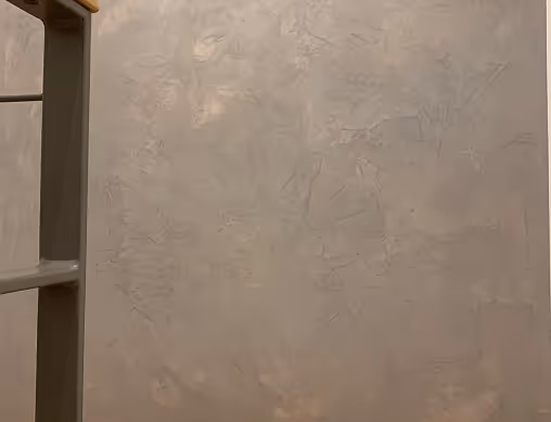 Beige strukturierte Wand mit Sicht auf ein graues Regal an der linken Seite.